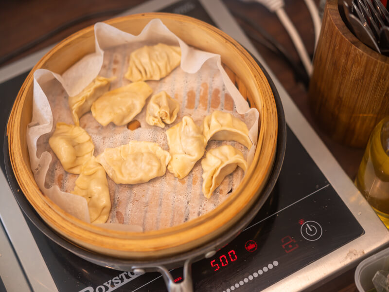 Close up of gyoza steaming in a bamboo steamer