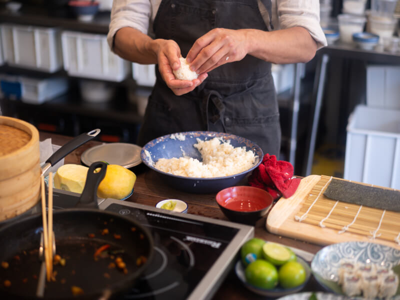 A person makes balls of rice by hand at a cooking course.