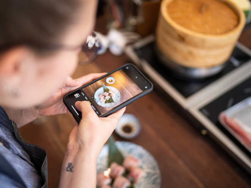 A person using a smartphone to take a photo of the food they've made