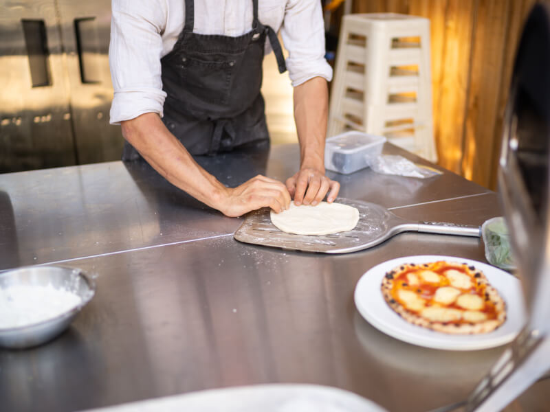 A man stretching homemade pizza dough.