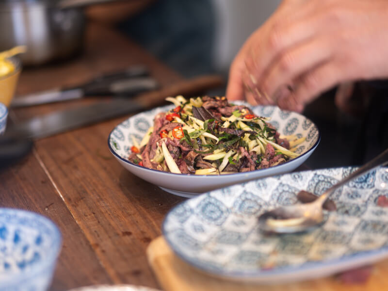 An Asian dish made of meat and vegetables sits on a blue patterned plate
