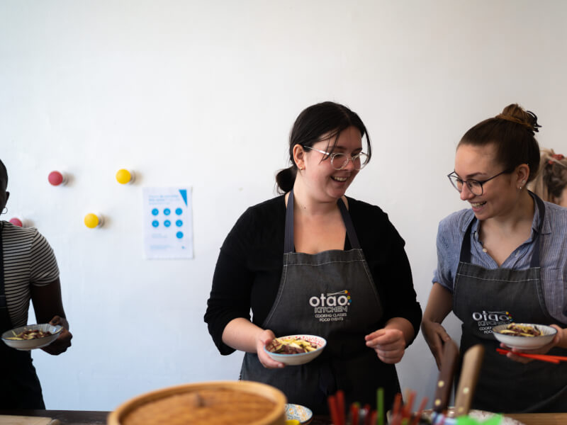 Two women smiling at each other at a cooking class
