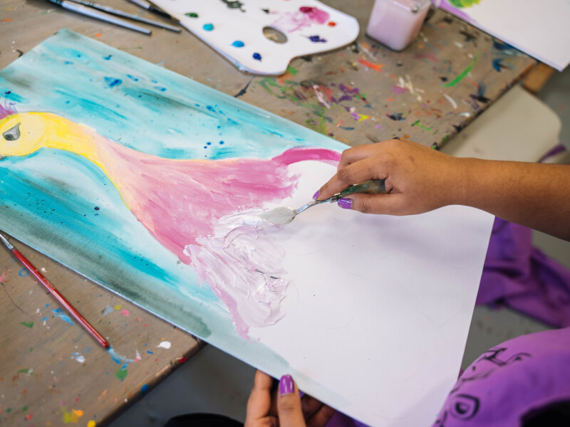 A close up picture of a colourful peacock painting on a wooden table