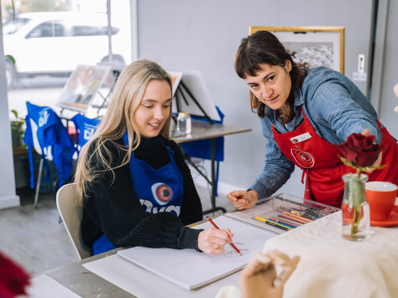 Teacher talking to a student at an art class.