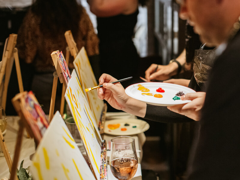 People painting with brushes and canvas in a paint and sip class