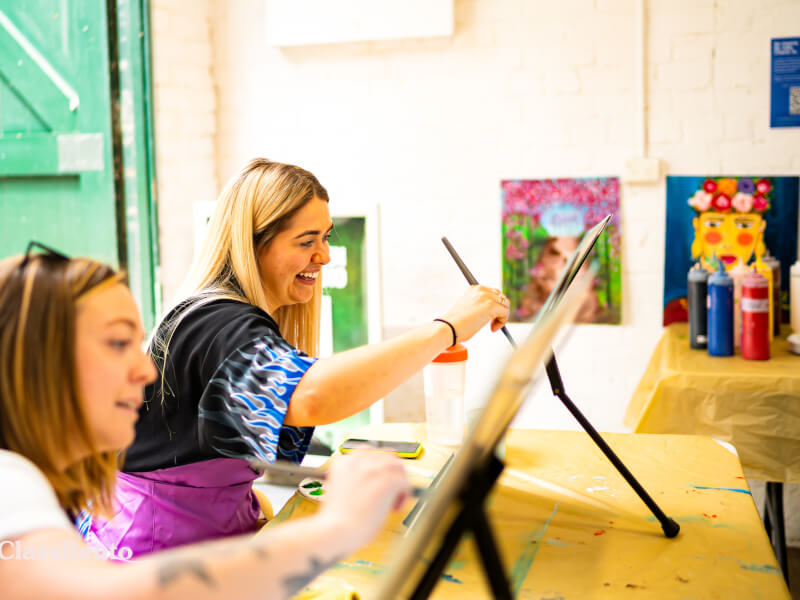 Two women painting at a hen party art class.