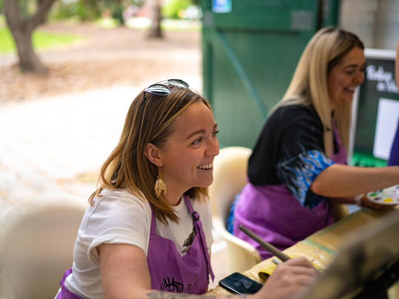 Two women smiling at a painting class.