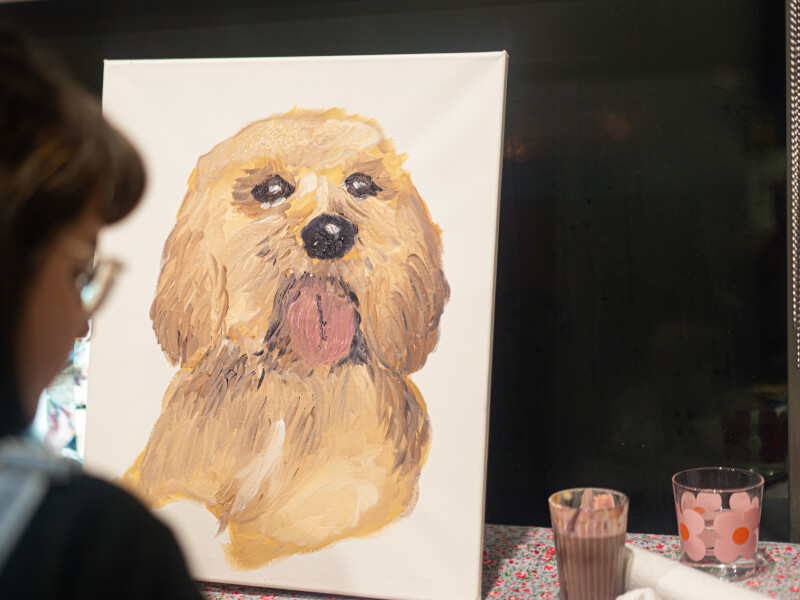 A woman is painting a portrait of a yellow and brown dog 
