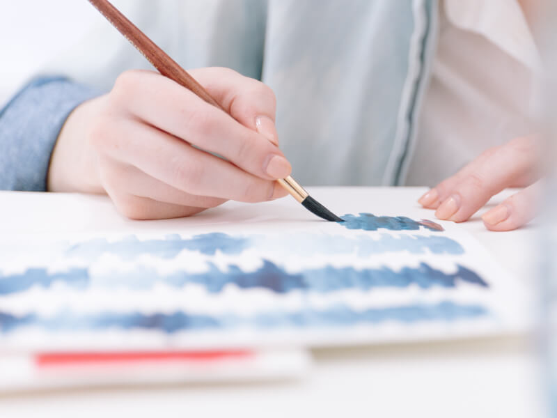 A closeup of blue paint being applied to paper.
