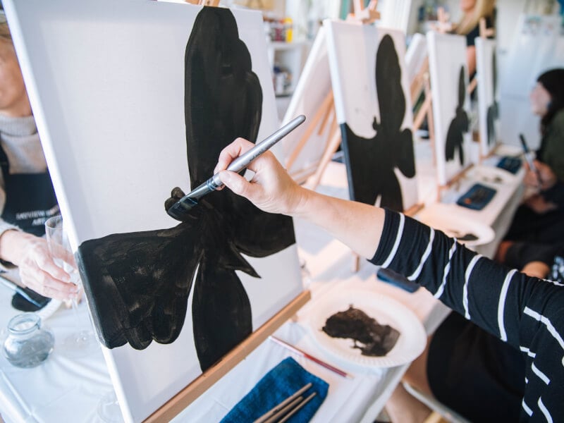 Person painting a black butterfly at a paint and sip
