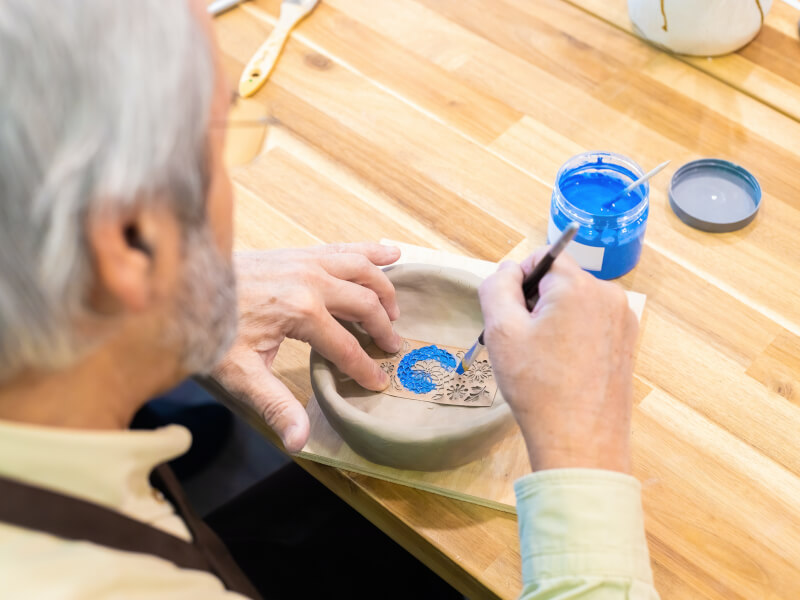 A man uses a stencil to paint ceramics in a class.