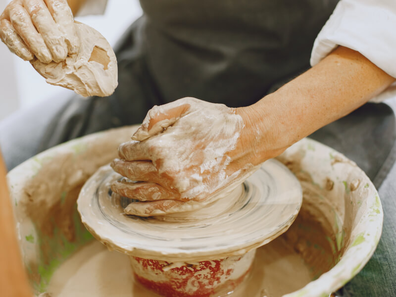 A closeup of a man throwing clay on the pottery wheel.