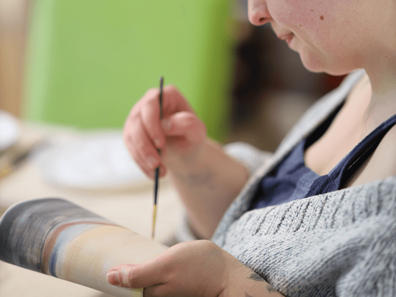 A close up of a person painting a pot at a Sculpt and Sip workshop