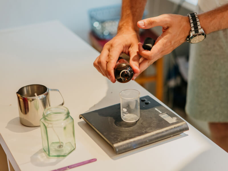Person weighing essential oils on a compact scale