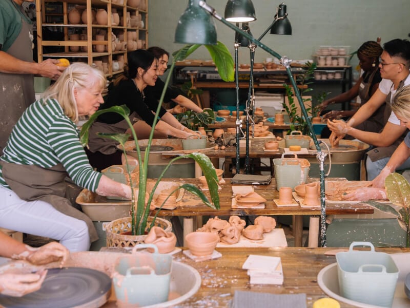 Wide shot of a group of people of different ages at a pottery class
