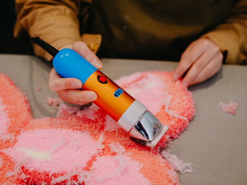 Hands using a tufting tool in a rug tufting class