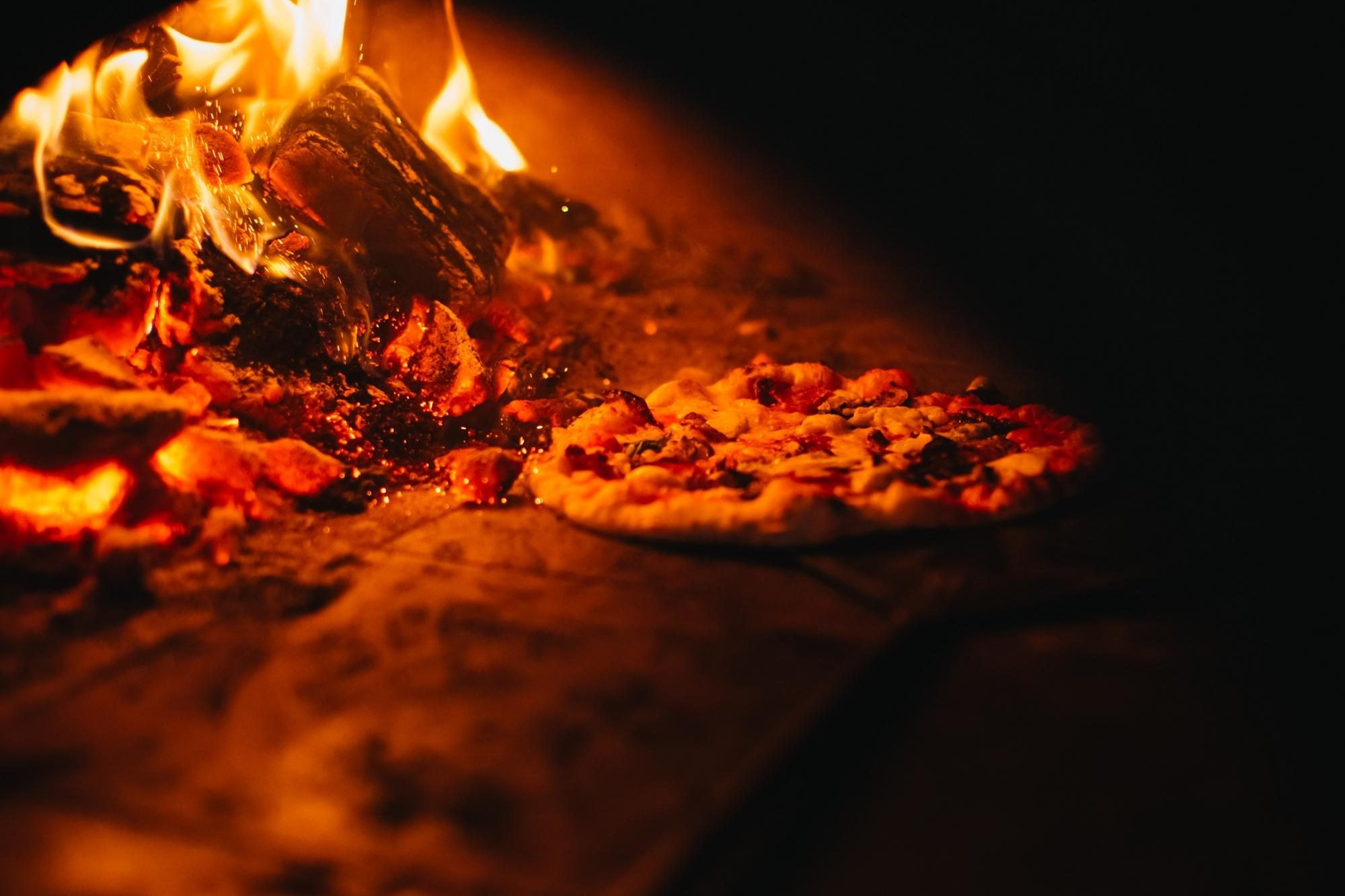 A Neapolitan pizza cooking in a wood fired oven