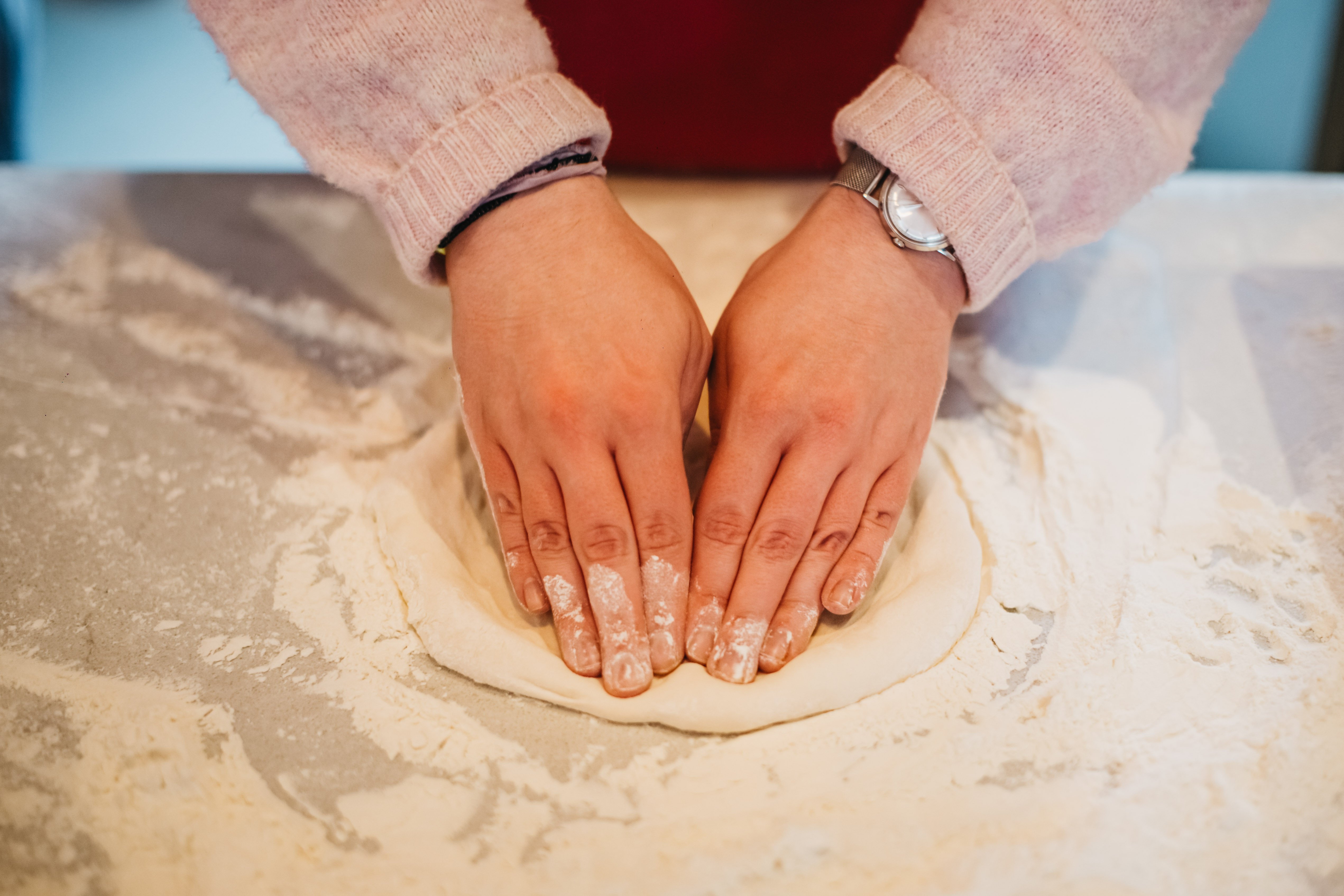 close up of hands kneading pizza dough