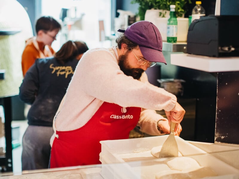 A ma scraping pizza dough at a vegan pizza making class. 