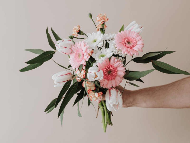 A person holds up a floral arrangement