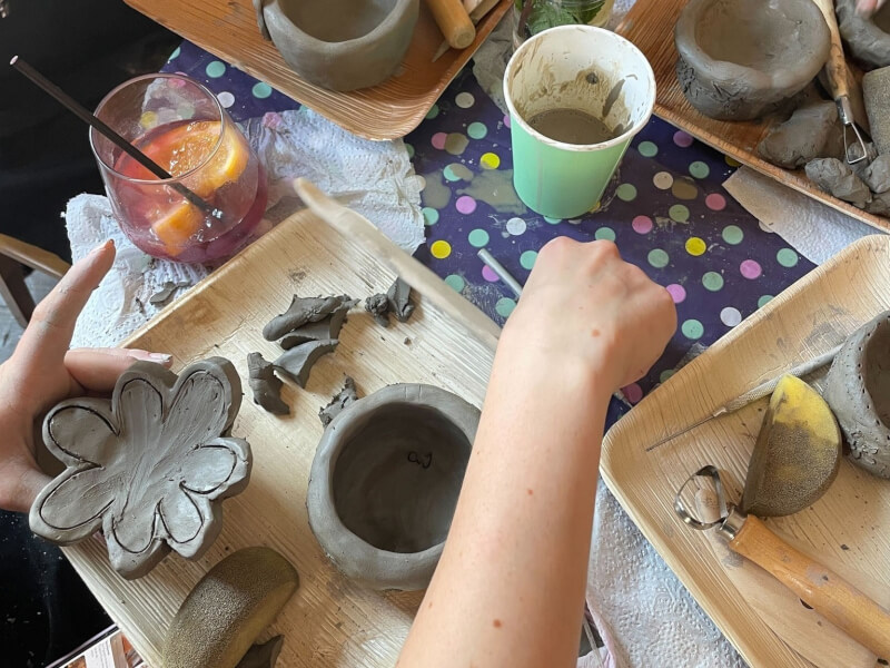 A close up of a person creating a clay plate shaped like a flower