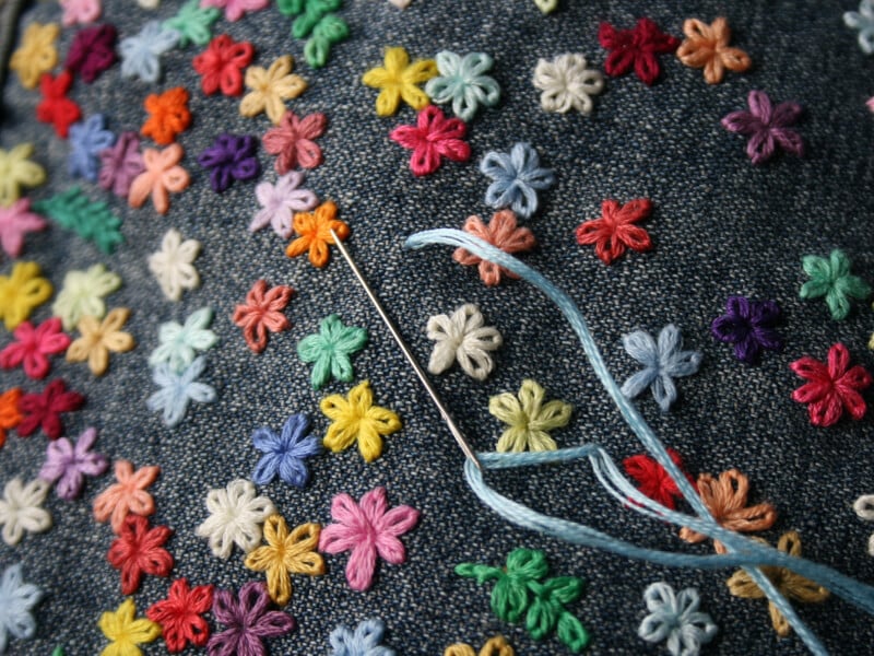 An example of hand embroidery on denim covered in colourful flowers.