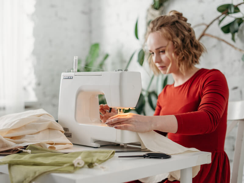A woman is learning how to use a sewing machine.