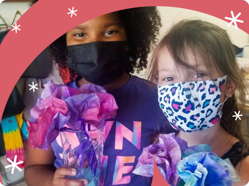 A pair of children holding flower vases.