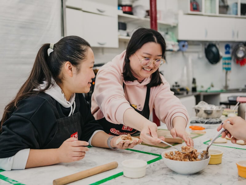 Two women smiling and laughing at a cooking class