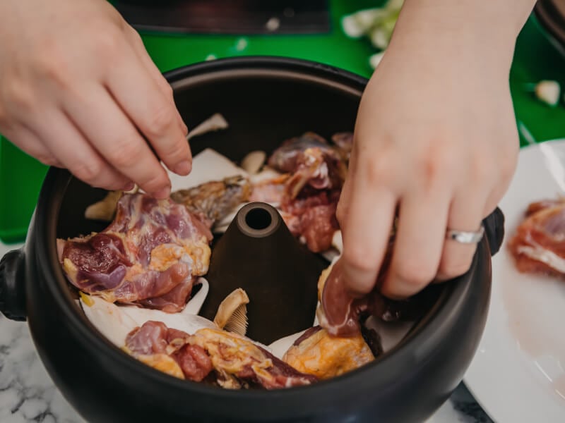 Close up of hands arranging ingredients in a Chinese hot pot