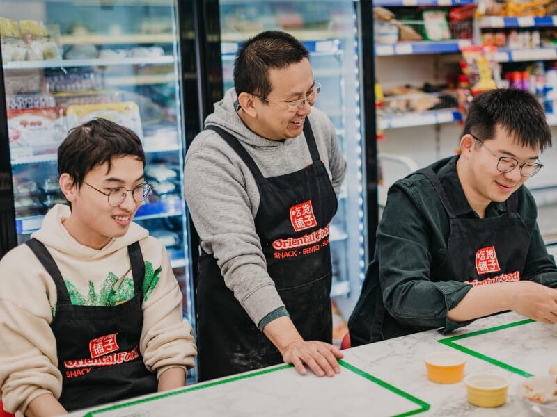 A man is teaching two other men how to make dumplings in a cooking class