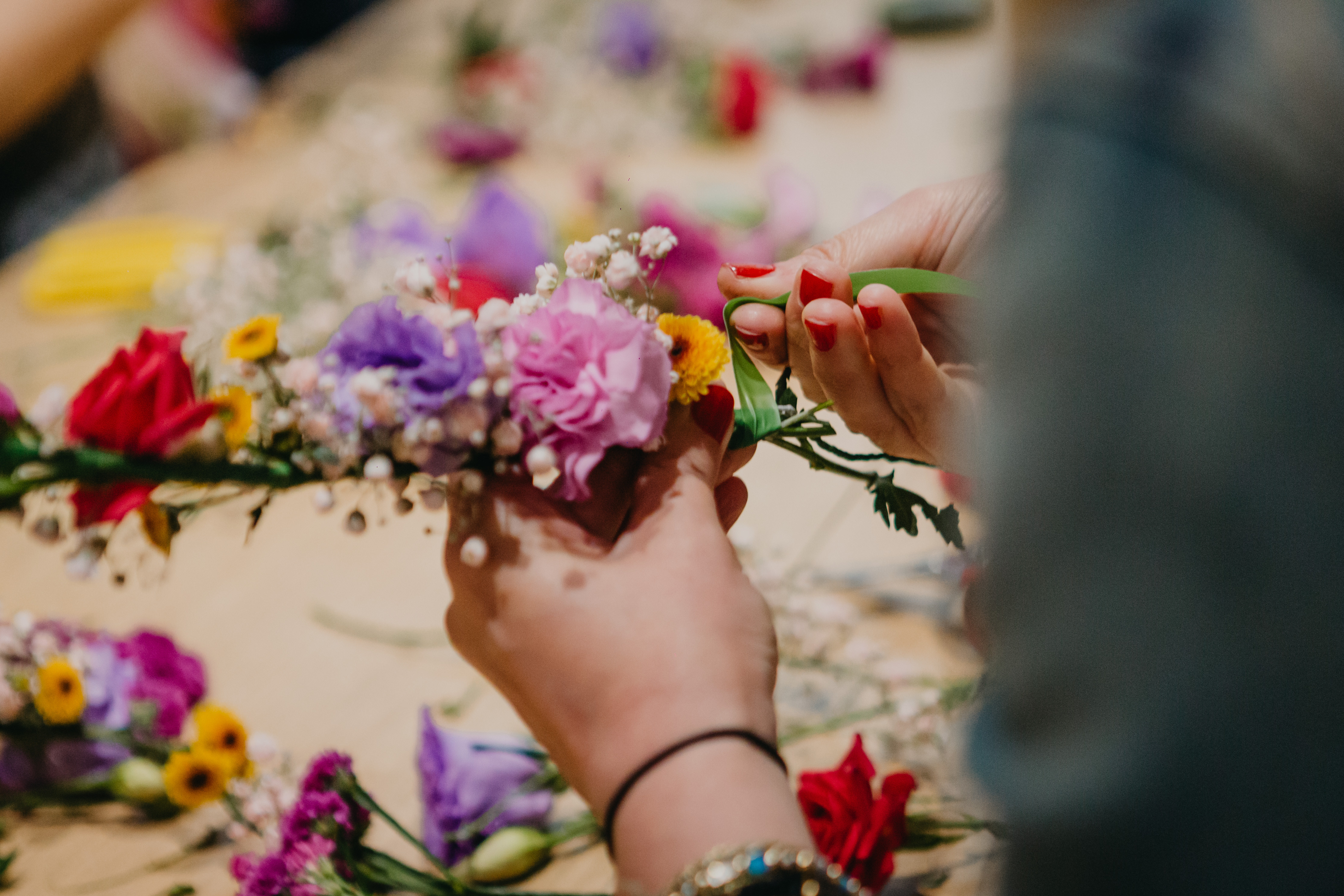 Close up of a person arranging a flower crown, shot from behind