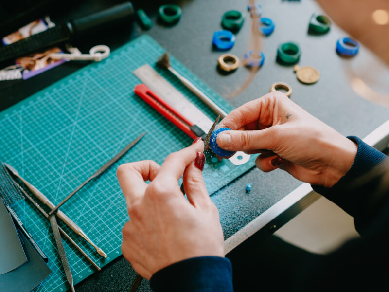 A close up of someone filing a wax ring mould at a jewellery class
