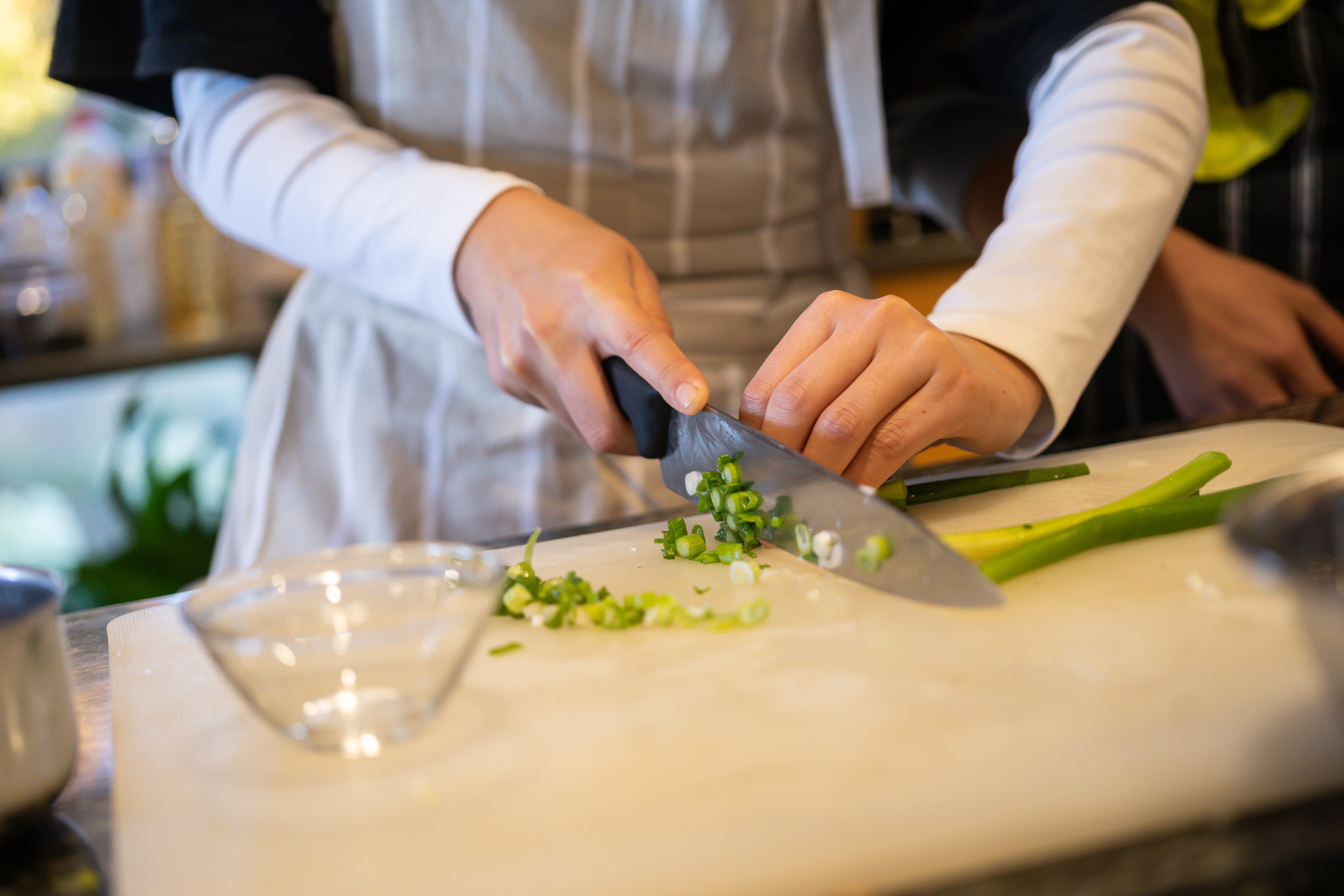 A person chopping green vegetables with a chef's knife