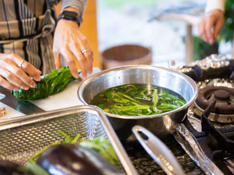 Close up of someone blanching green vegetables in a stainless steel pan