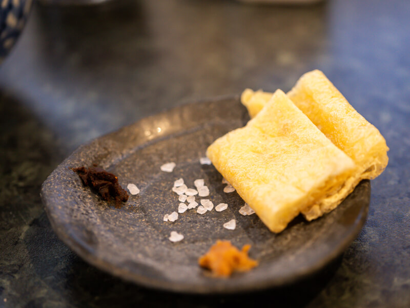 A small black plate of fried bean curd with garnish