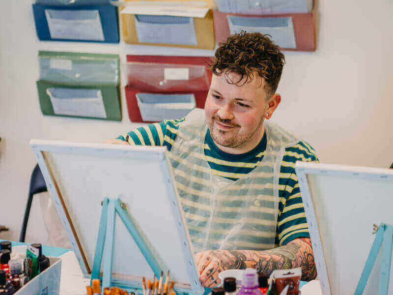 Man painting on a canvas in a painting class