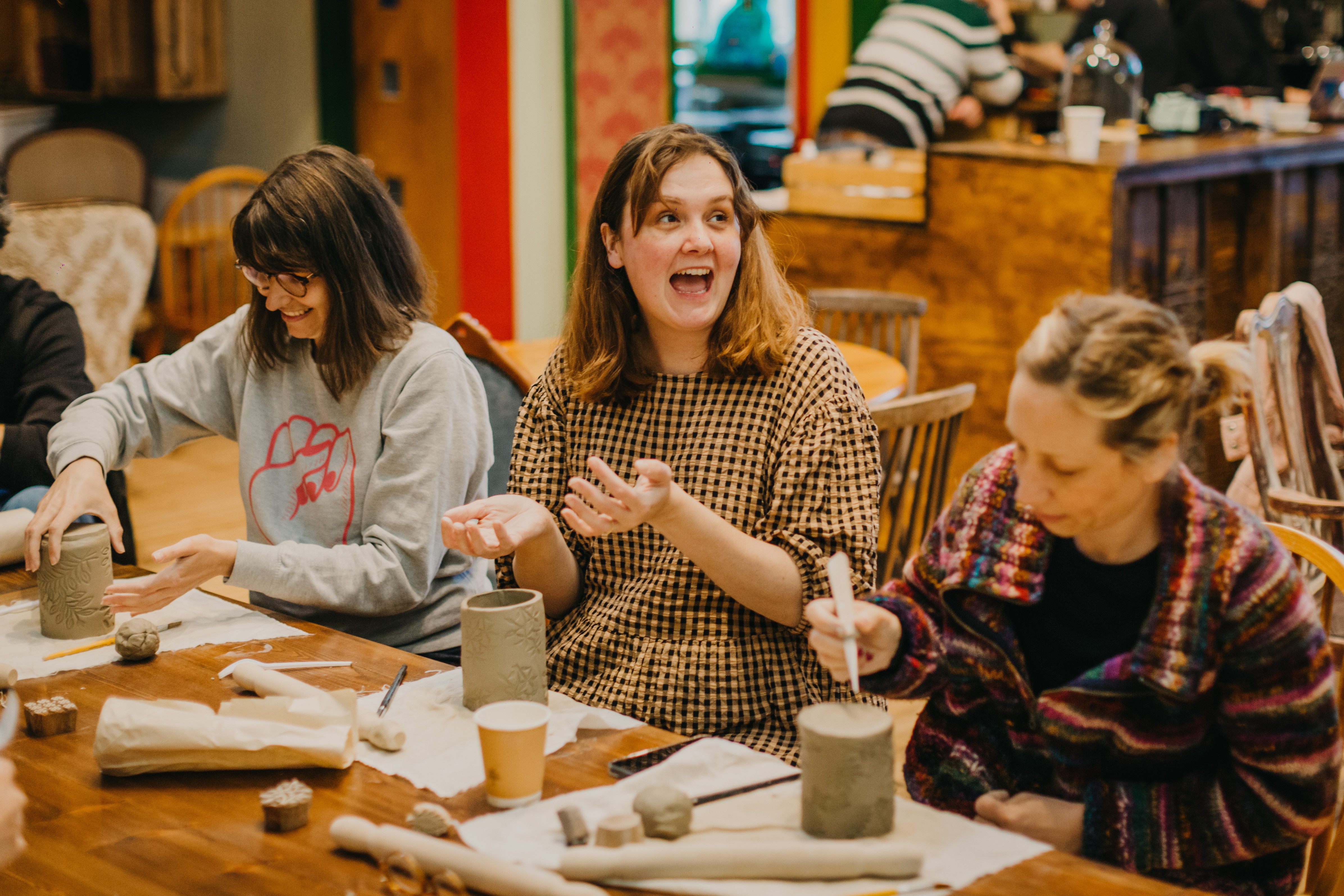 Three women smiling and laughing at a sculpting class
