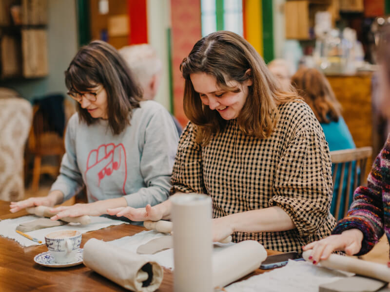 Three women working at a hand building pottery class
