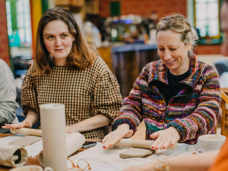 Two women rolling out clay at a pottery class