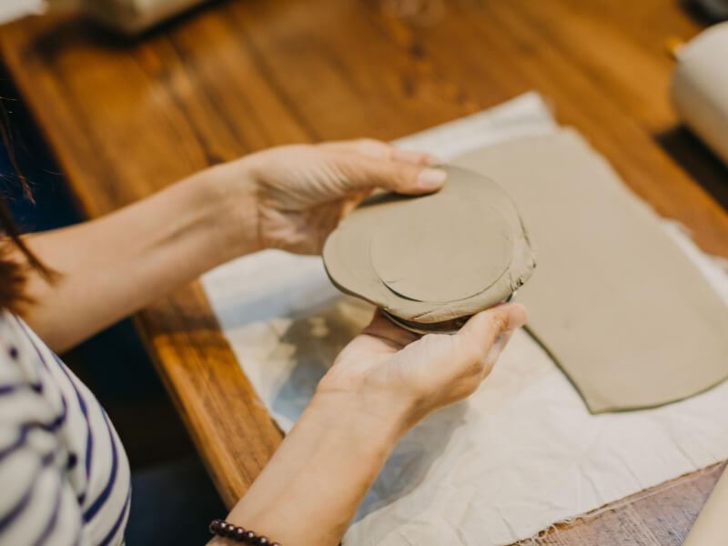 Close-up image of a person cutting out a circular shape from a sheet of clay.