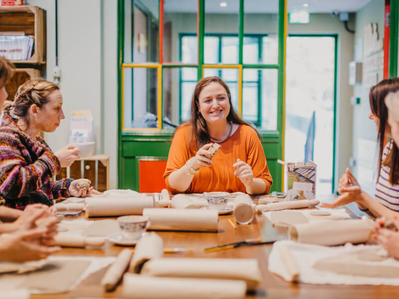 A group of women sitting around a table as they work at a sculpting class