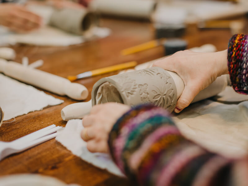 A woman rolling homemade clay in a pottery making class.