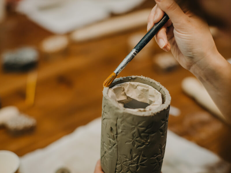 Person decorating clay at a pottery class. 