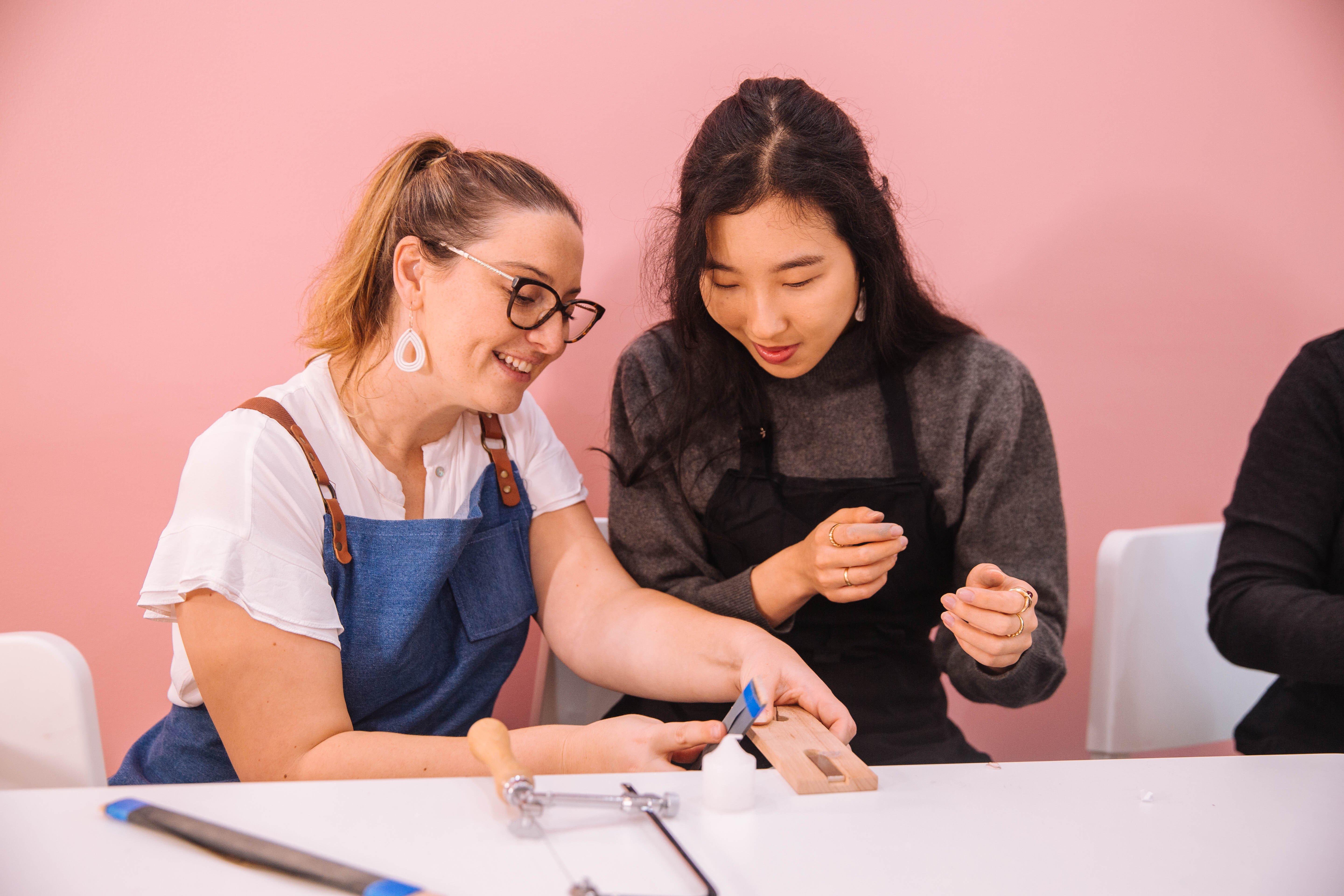 A teacher helps a student at a jewellery making class