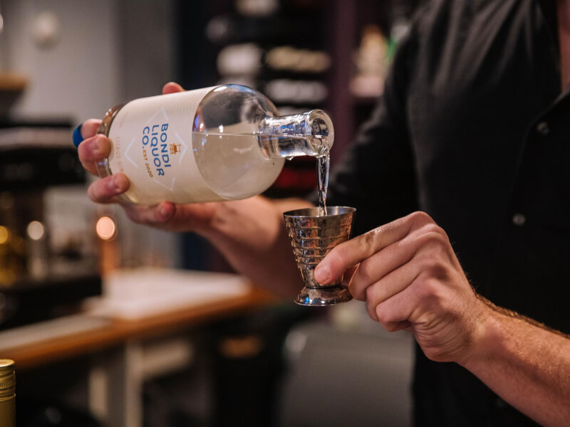 Hands pouring a measure of gin into a jigger