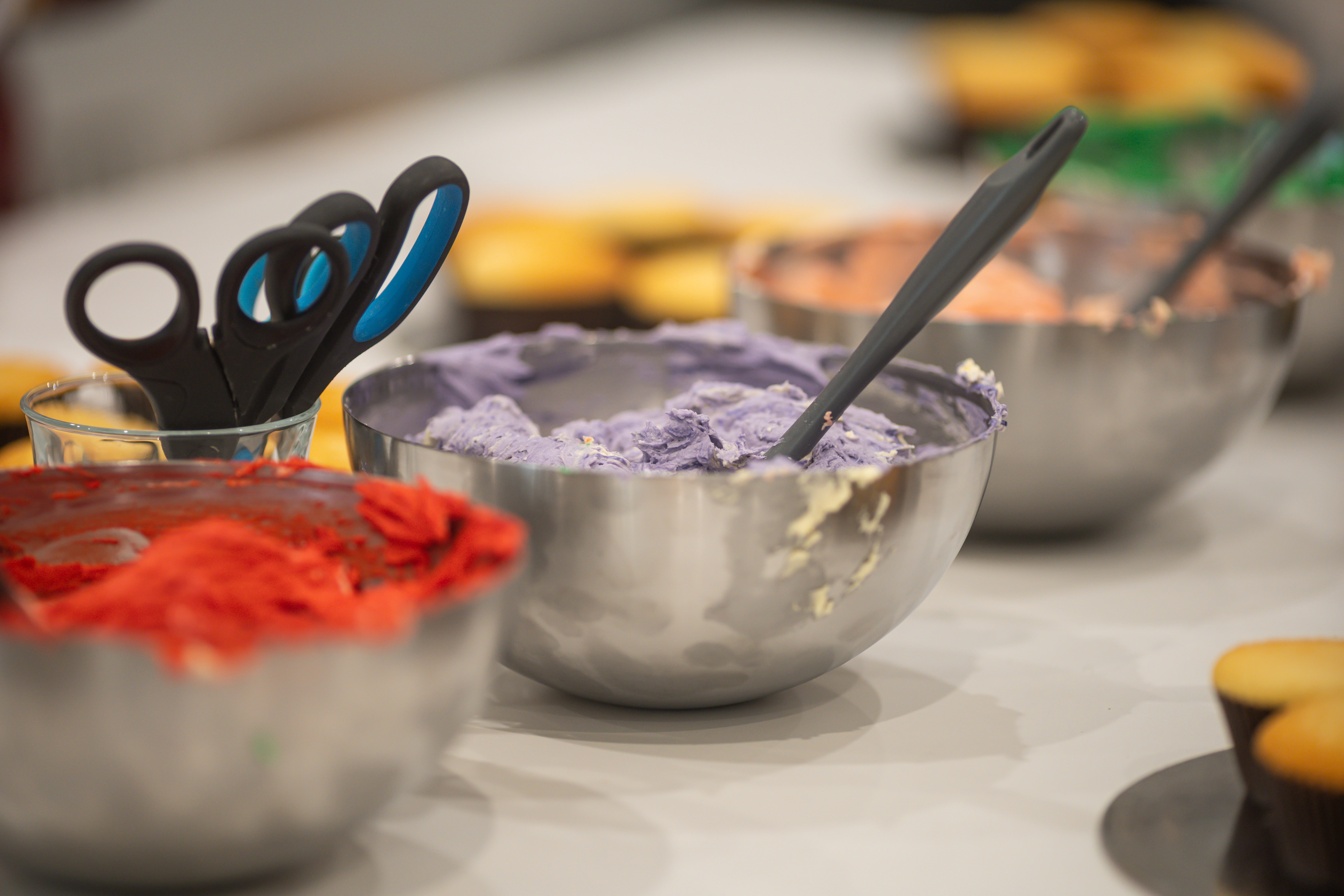 A row of metal bowls containing different coloured icing