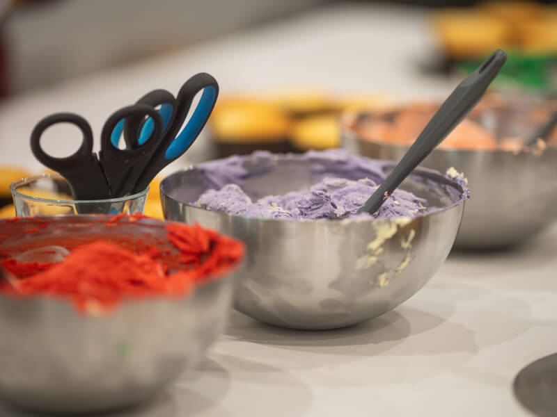 Three metal bowls filled with coloured icing