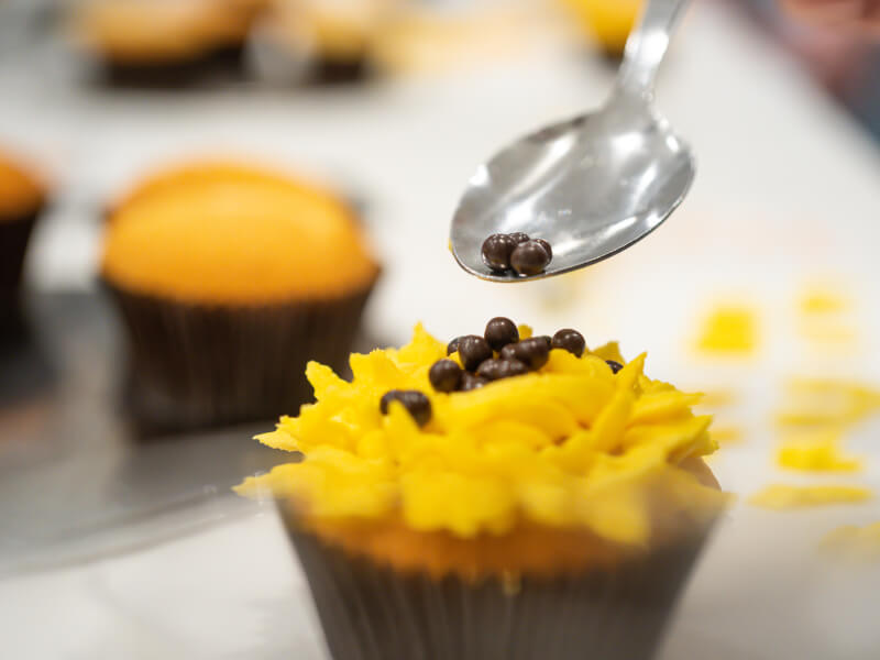 A closeup of a cupcake being decorated in a baking class.