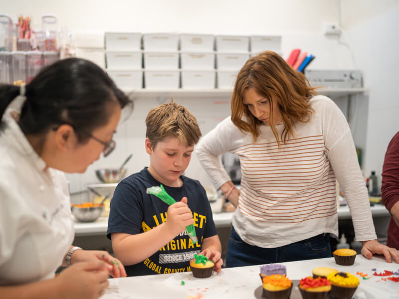 A mother and son try a cupcake decorating class together.